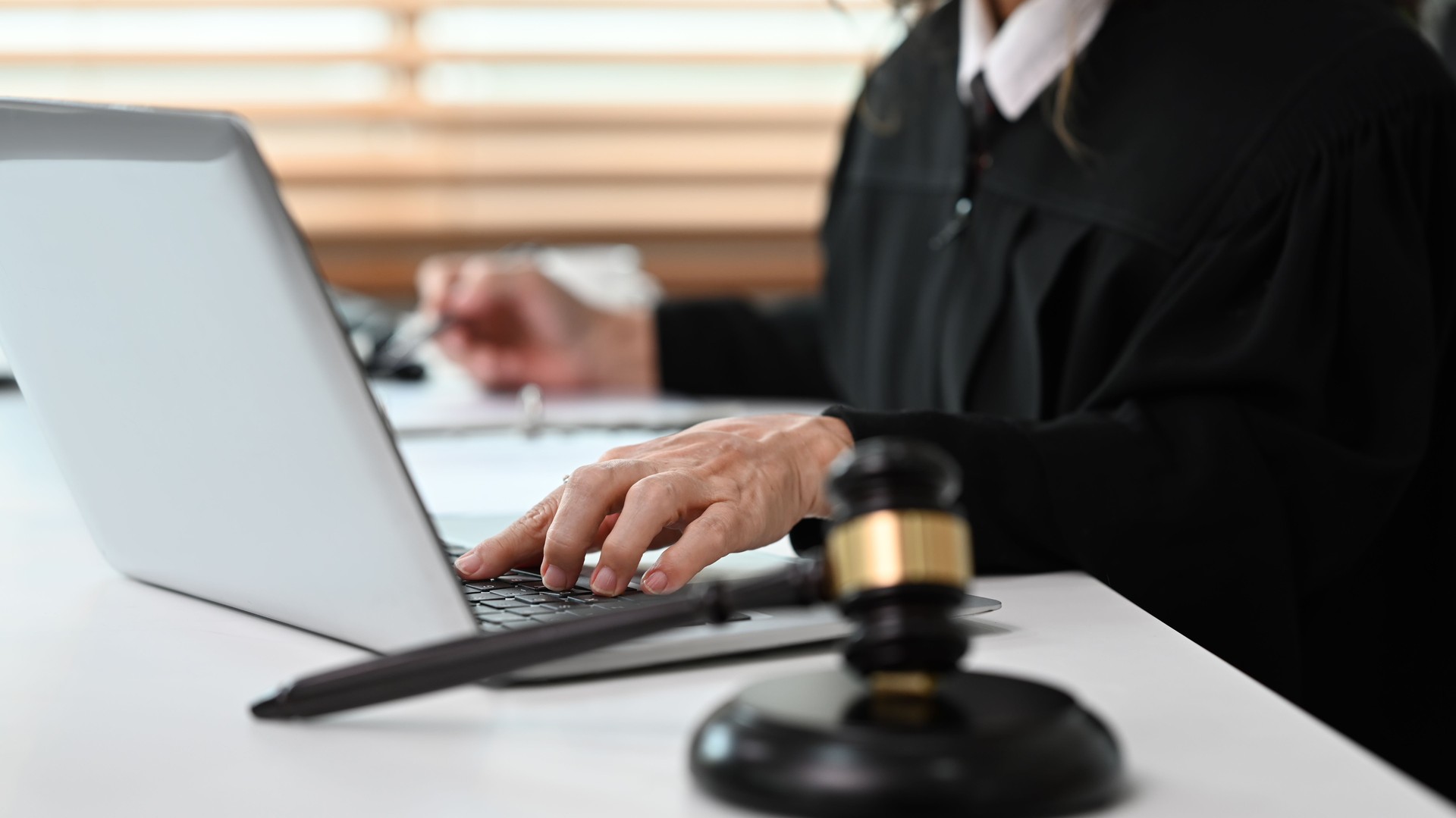Senior female lawyer reading judiciary law document and using laptop at her workplace.